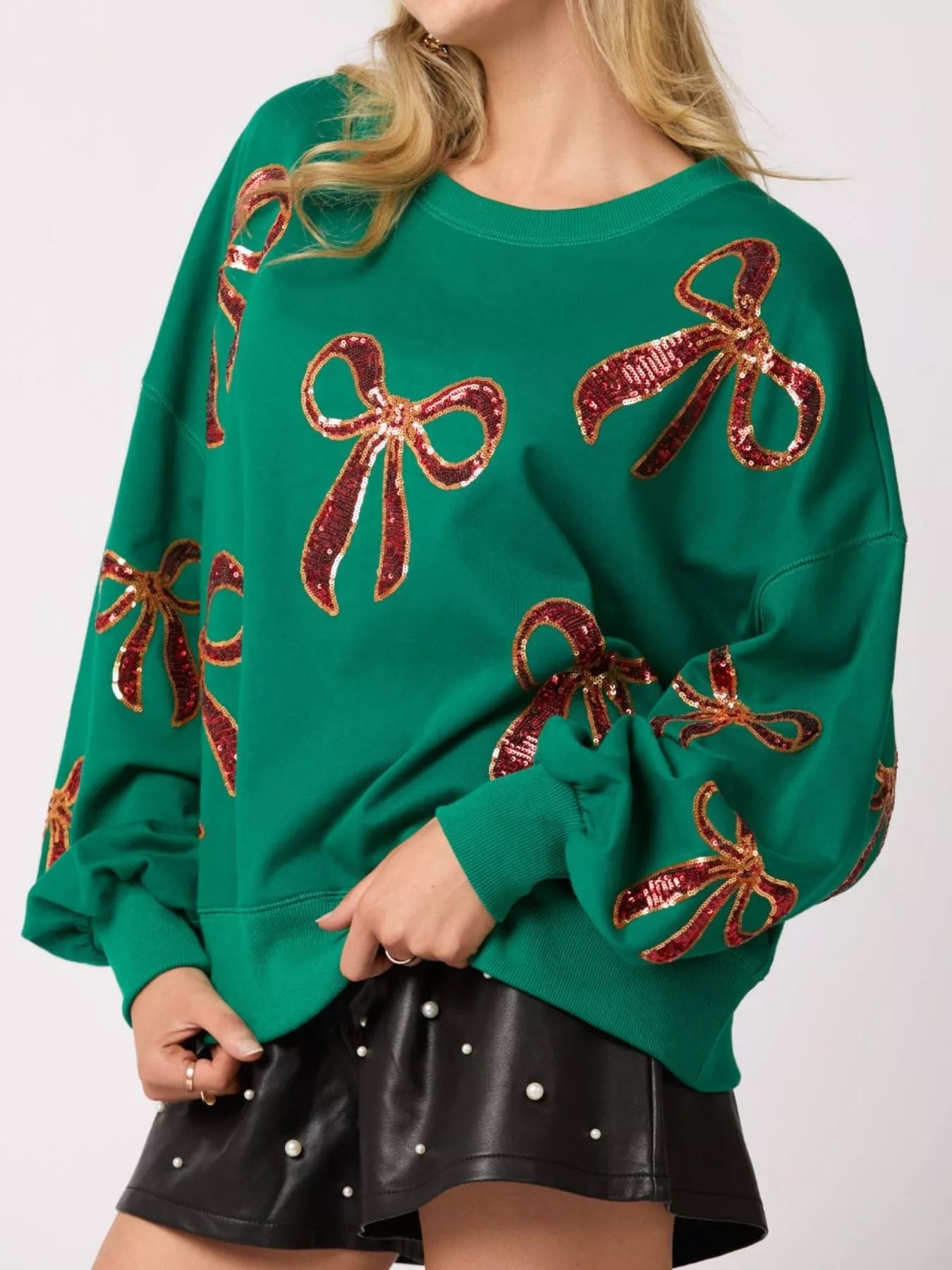 “Front view of women wearing a cozy Christmas sweatshirt with sparkling sequin bow, perfect festive holiday outfit for winter celebrations.”
